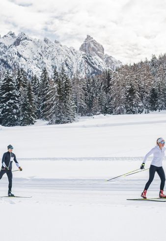 A man and a woman cross-country skiing in the Dolomites